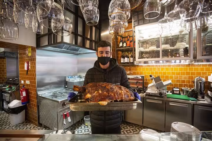 Chef in Porto restaurant presenting a roasted dish, highlighting authentic culinary experiences on food tour.