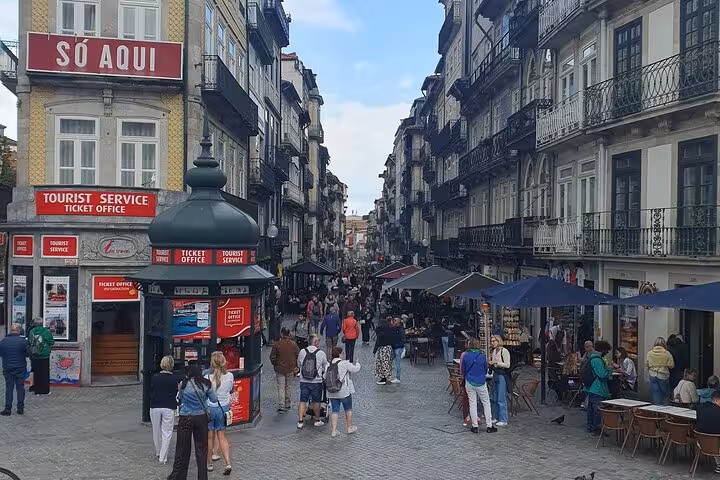 Bustling Porto street scene with tourists and locals enjoying outdoor cafes and historic architecture.