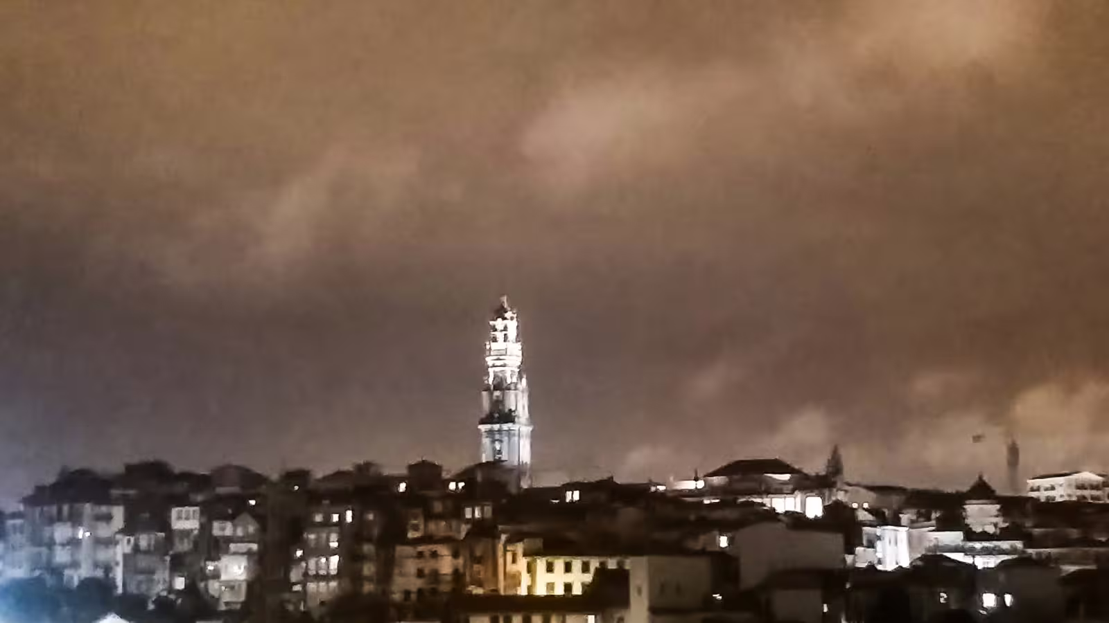 Illuminated Clérigos Tower against a dramatic night sky in Porto, showcasing the city's iconic skyline on a private night tour.