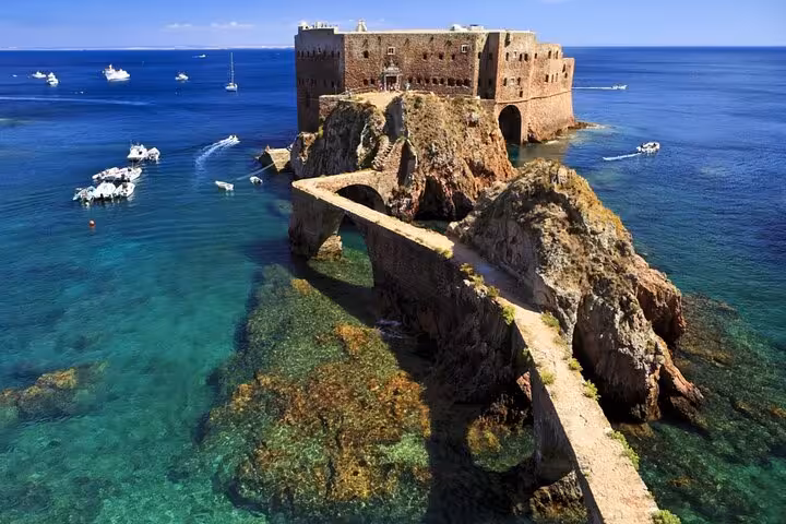 Ancient stone fort on rocky island connected by arched bridge, surrounded by turquoise Atlantic Ocean waters