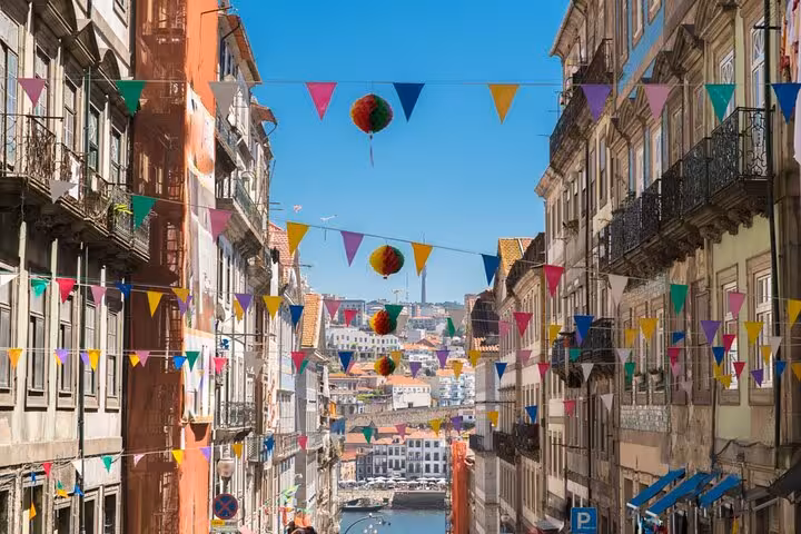 Colorful bunting flags and decorative balls strung between historic buildings on a sunny Porto street