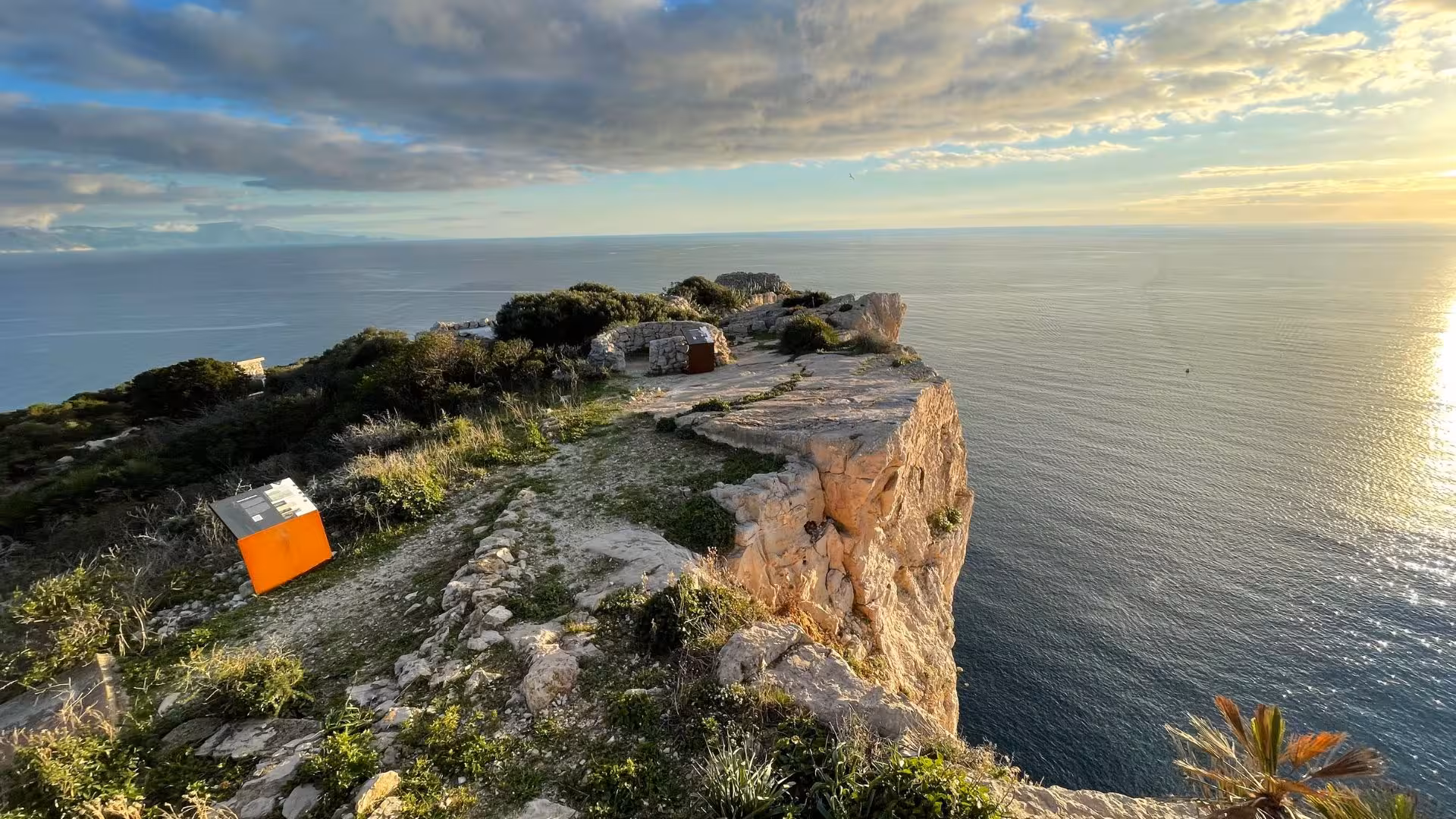 Cliffside view in Porto Conte Park, Alghero, overlooking the Mediterranean at sunset, ideal for trekking adventures.