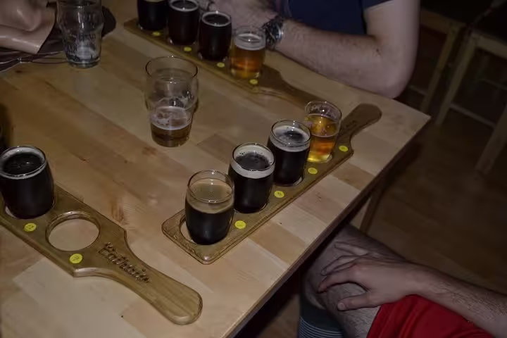 A variety of craft beers in tasting glasses on a wooden paddle at a Porto brewery, showcasing diverse flavors and colors.