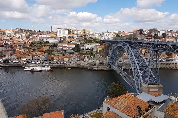 Stunning view of Porto's iconic Dom Luís I Bridge and colorful hillside buildings on a sunny day, perfect for a city hall walking tour.
