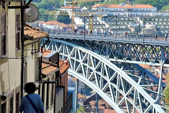 View of Porto's iconic Dom Luís I Bridge with pedestrians and scenic cityscape, perfect for a coastal city tour.