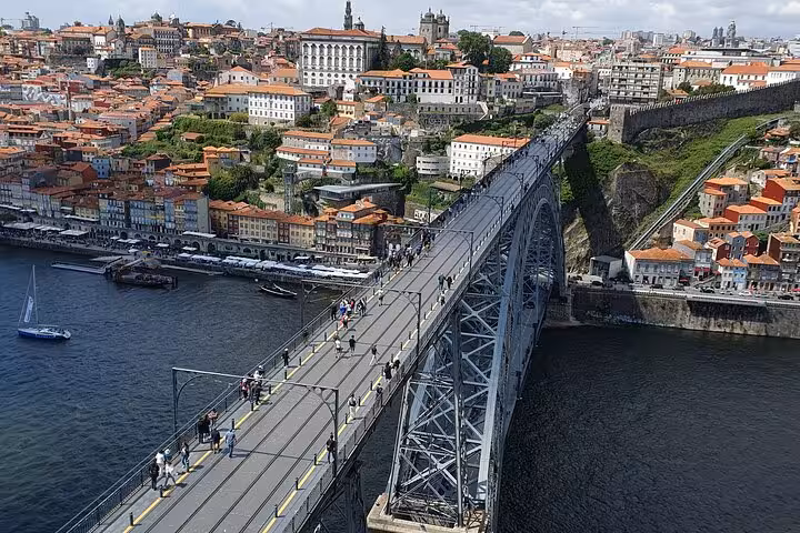 Aerial view of Porto's iconic Dom Luís I Bridge crossing the Douro River with vibrant cityscape in the background.