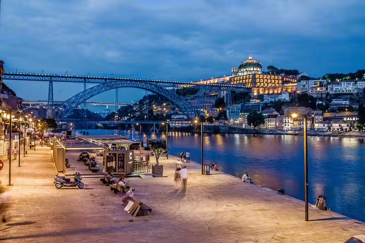 Evening view of Porto's riverside with the iconic Dom Luís I Bridge, perfect for a sunset stroll on a Portugal tour.