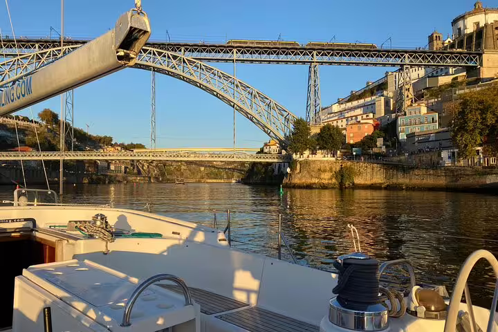 Scenic Douro River boat tour in Porto with iconic bridge views, featuring complimentary wine and snacks on a sunny day.