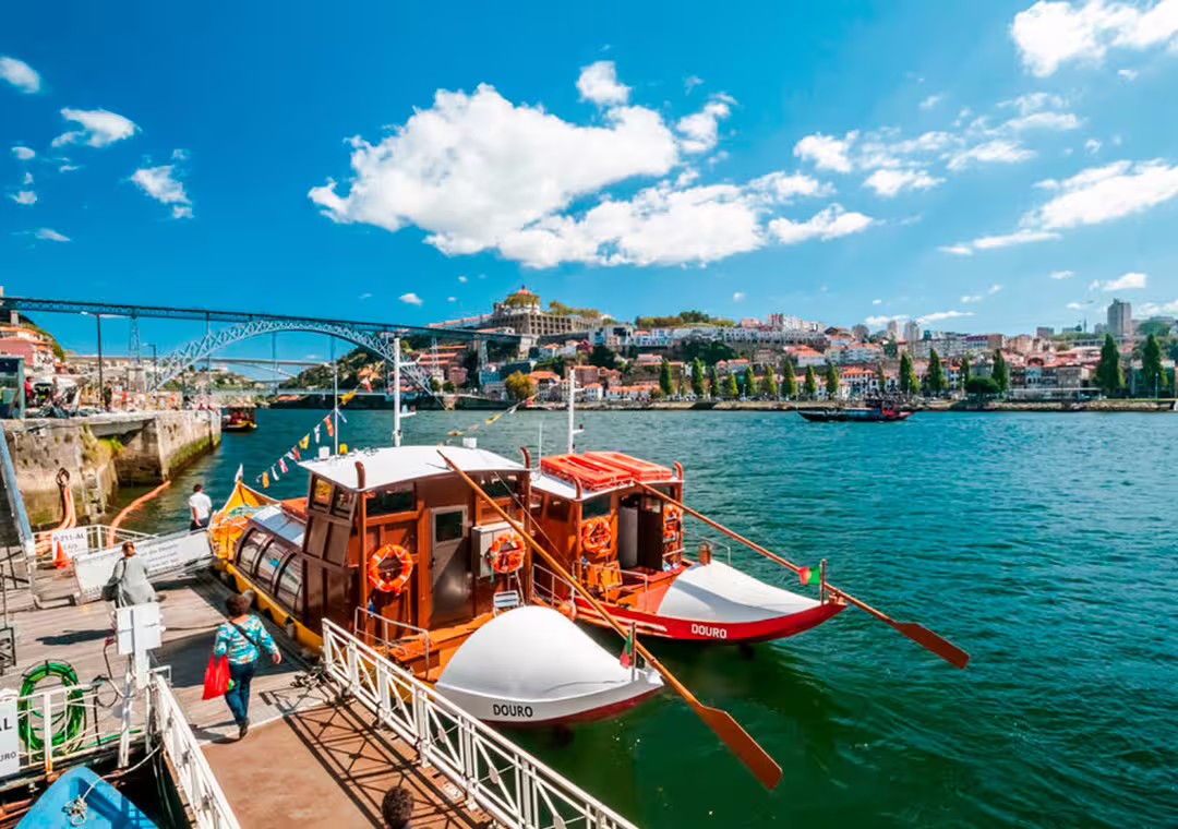 Traditional boats on the Douro River with Porto's picturesque skyline and iconic bridge in the background, ideal for a scenic half-day tour.