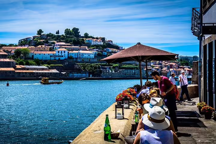 Relaxed dining by the Douro River in Porto during a private tour from Lisbon, with scenic hillside views.