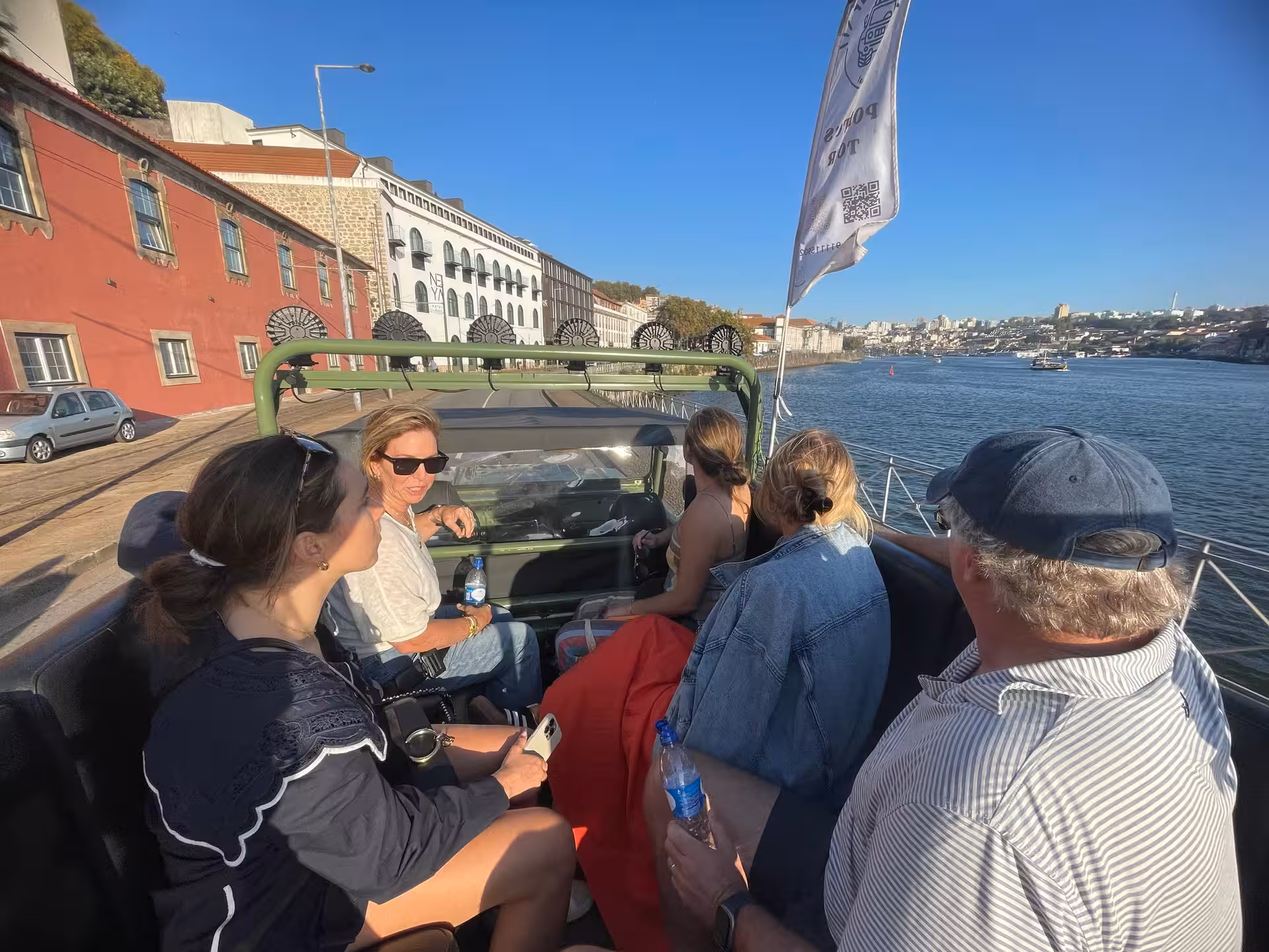 Guests riding open-top jeep along the Douro River in Porto, scenic waterfront views and historic sites