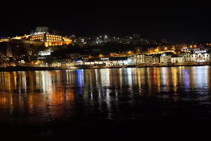Night view of Porto's illuminated waterfront reflecting on the Douro River, highlighting the scenic route from Lisbon.