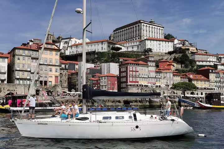 Scenic view of a sailboat on the Douro River with Porto's historic architecture in the background during a private tour.