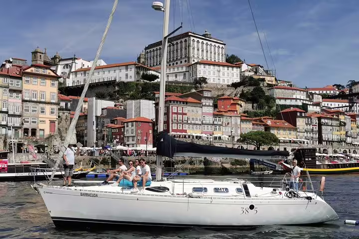 Sailboat cruising along the Douro River with picturesque Porto cityscape in the background, ideal for sunset tours.