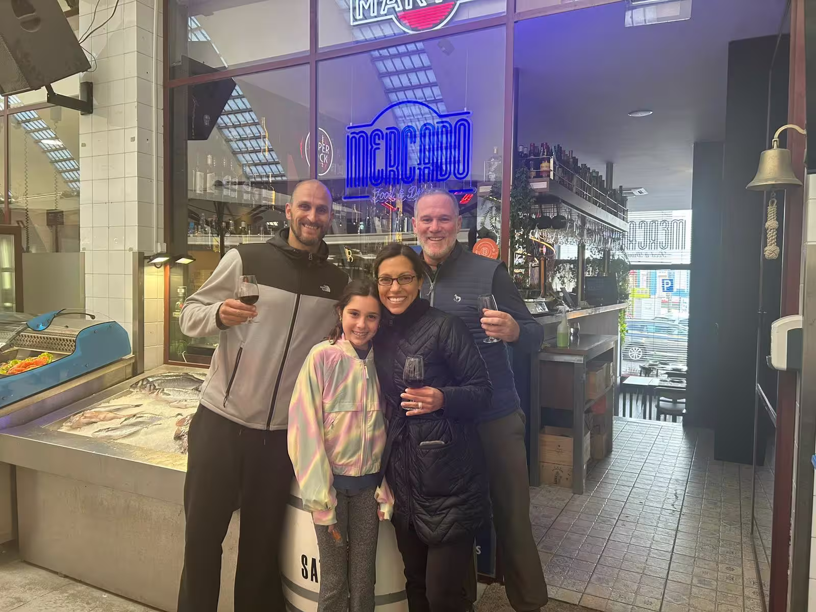 Smiling group poses at a seafood market, savoring Porto's culinary delights on an e-bike tour.