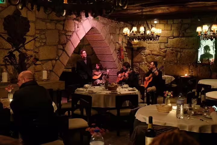 Cozy Porto restaurant with diners enjoying live Fado performance, rustic stone walls, intimate lighting, and authentic Portuguese ambiance.