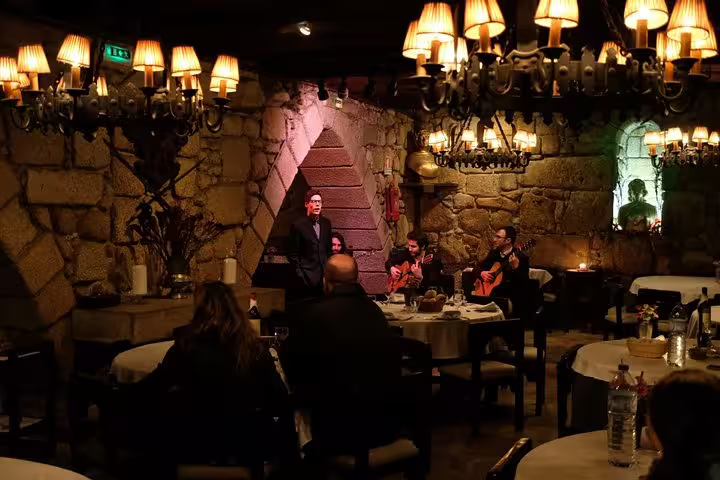 Cozy Porto restaurant setting with live Fado music, warm lighting, and guests enjoying a traditional Portuguese dinner experience.
