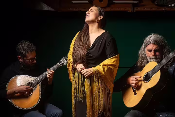 Musicians perform traditional Fado music with passion by Porto's riverfront, featuring a singer in a yellow shawl and guitarists.