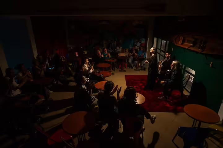 Intimate Fado performance by the riverfront in Porto, featuring live musicians and an engaged audience in a cozy setting.