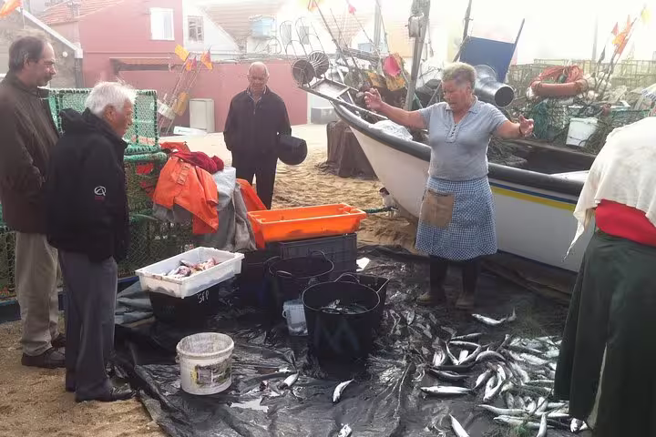 Local guide explaining fish varieties to tourists at a traditional Porto fishing dock, enhancing the private tour experience.