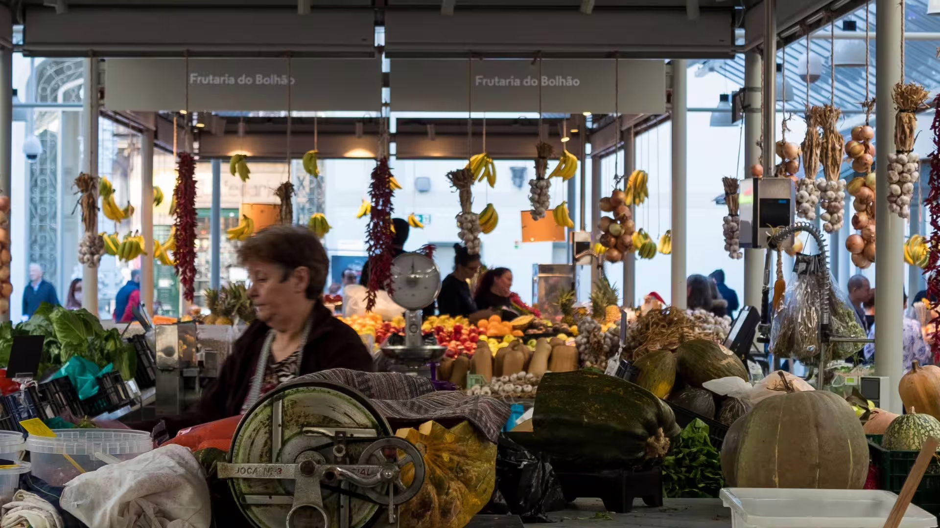 Image of a vendor in her stand filled with local products at Bolhão Market during Cooltour Oporto's Porto Food Tour