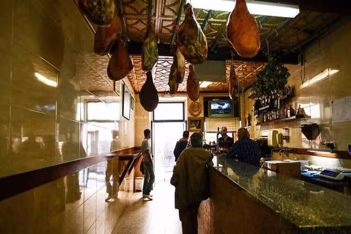 Traditional Porto deli with hanging cured meats in a cozy, rustic setting ideal for a Portuguese culinary tour.