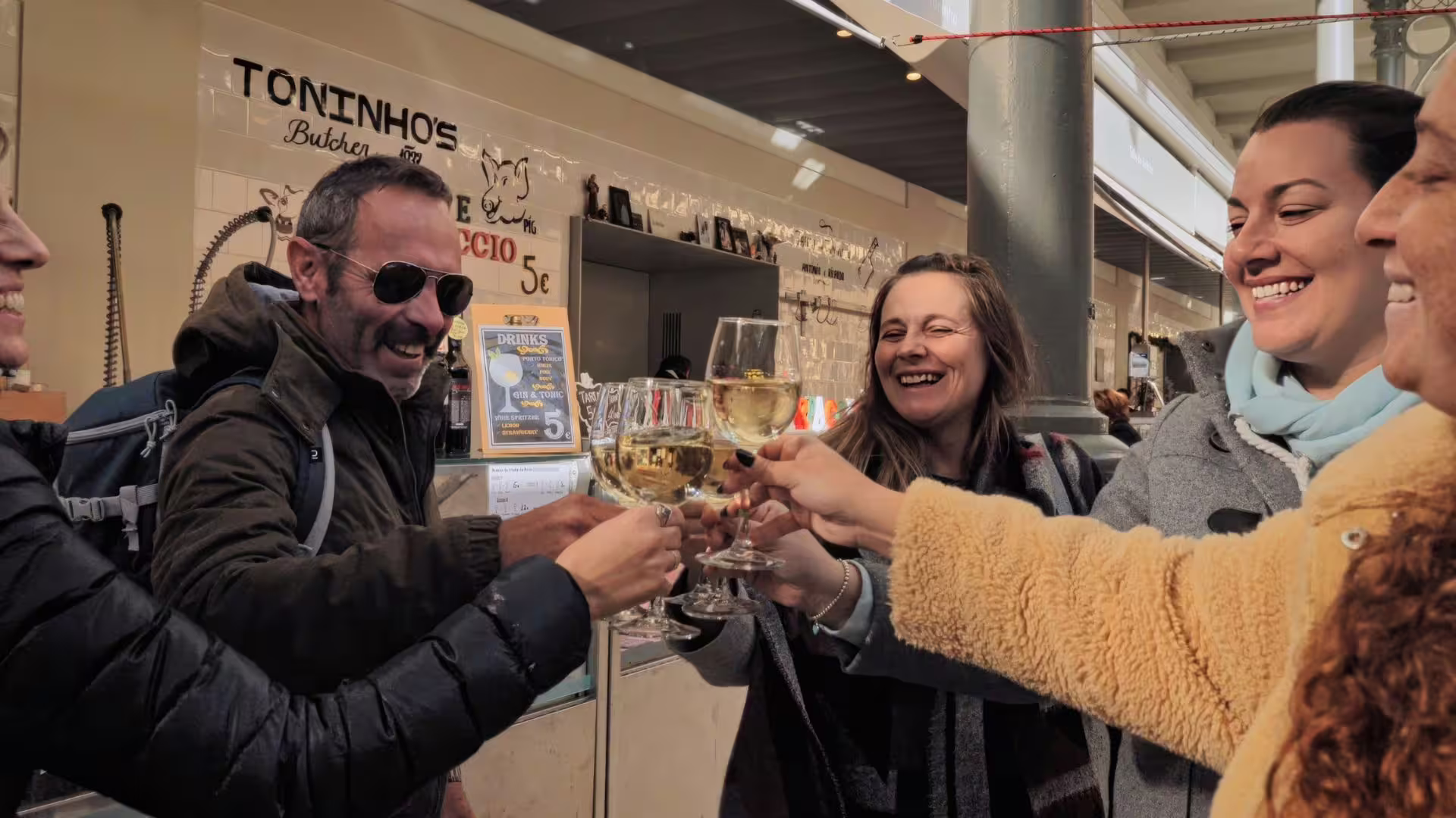 Tour guide and guests raising glasses of white wine at Bolhão Market during Porto Food Tour