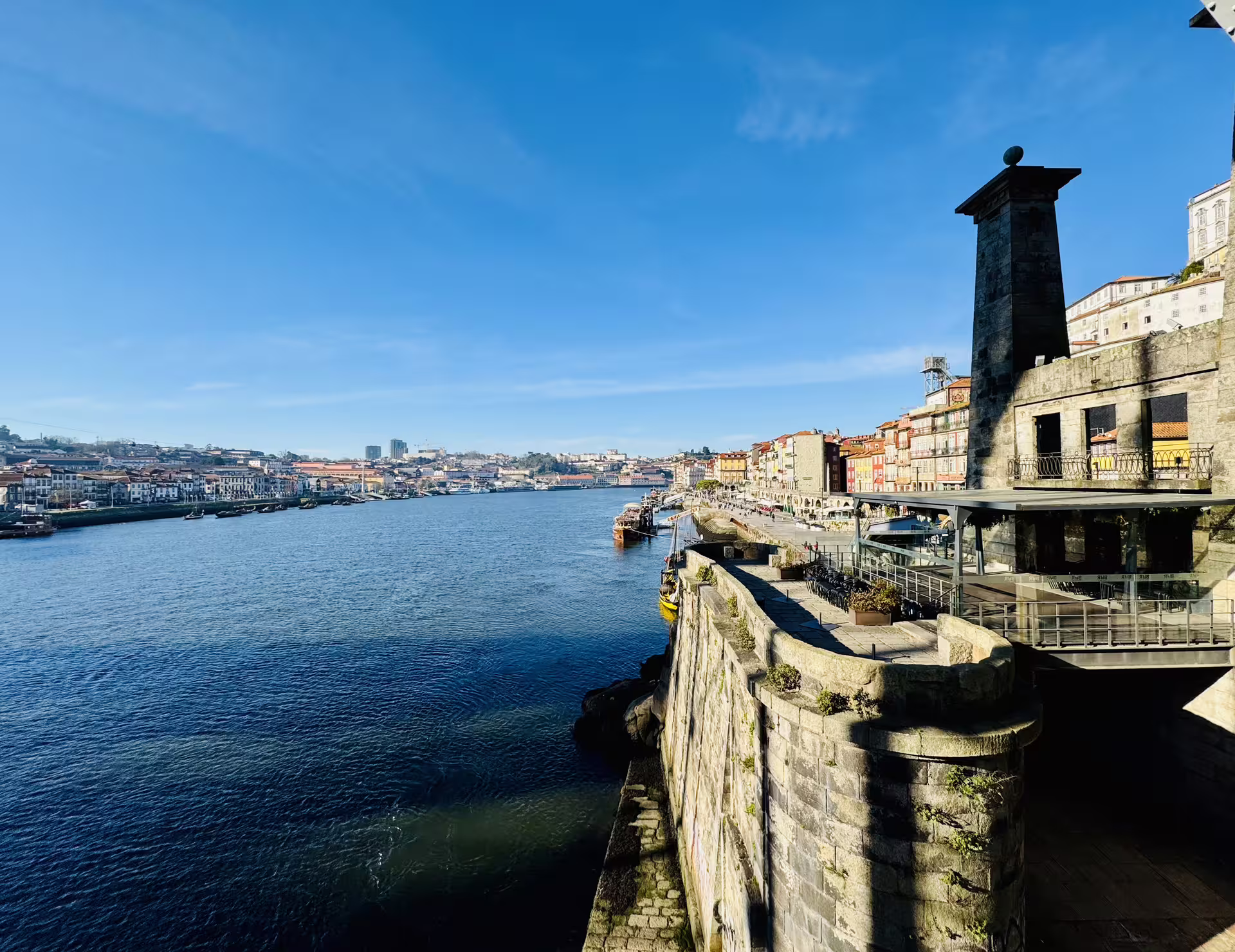 Scenic view of Douro River with historic Porto and Gaia waterfronts under a clear blue sky, ideal for a walking tour.