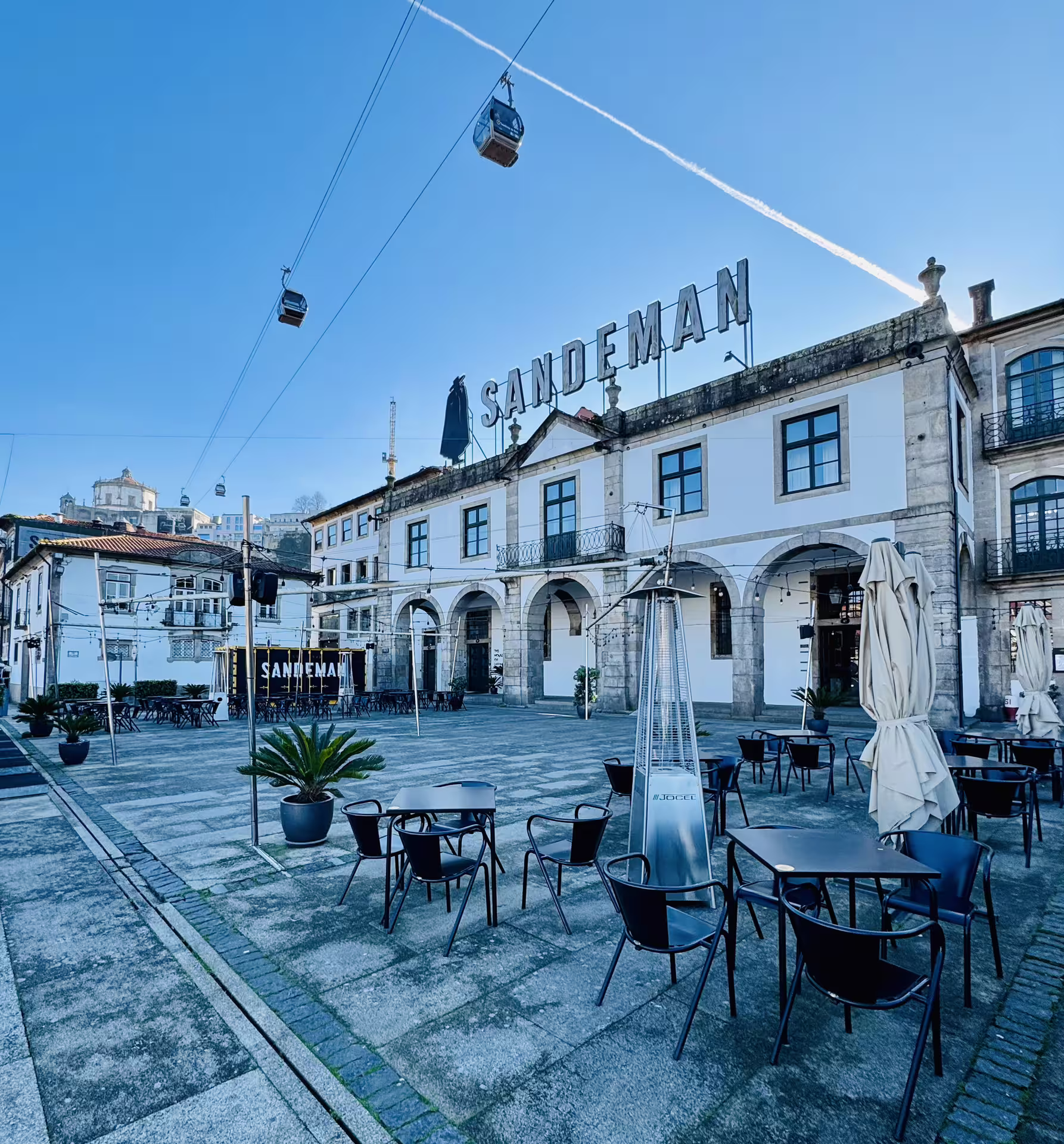 Historic Sandeman building and cable cars on a sunny day in Gaia, featured in the Porto and Gaia Douro walking tour.