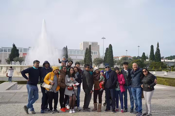 Group of tourists enjoying a scenic stop at a fountain during the Porto to Lisbon transfer with visits to Nazaré, Alcobaça, and Óbidos.