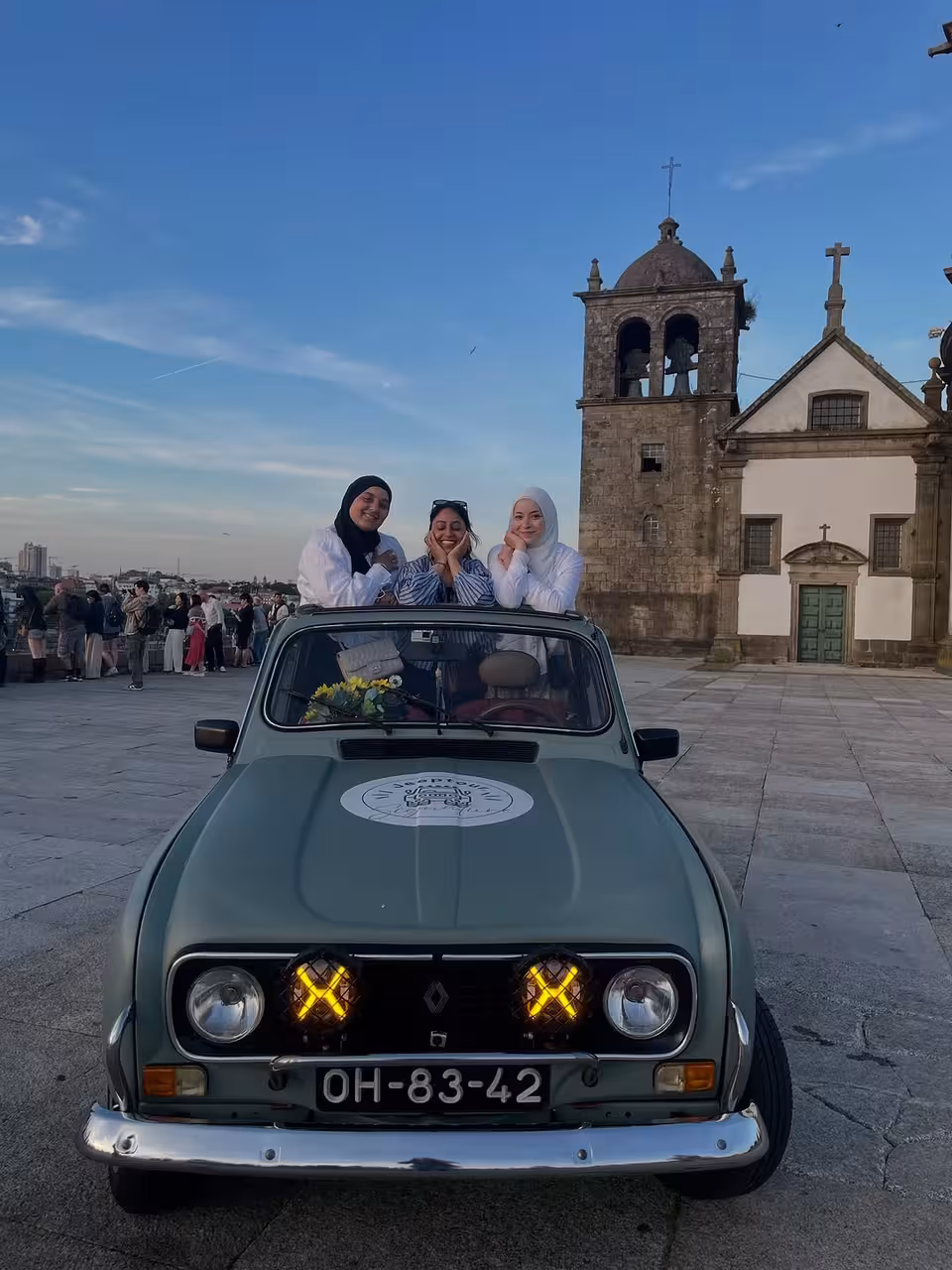 Vintage Renault on Porto night tour, guests posing by historic church near Douro River viewpoints at dusk