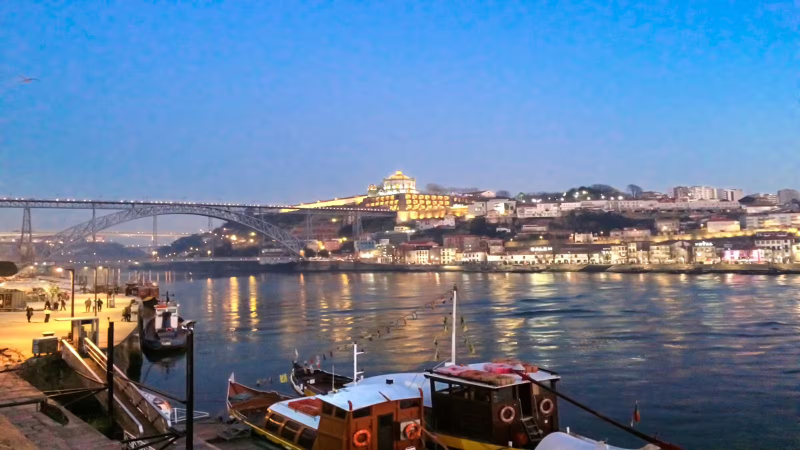Scenic night view of Porto's illuminated riverside and iconic Dom Luís I Bridge, perfect for a private night tour experience.
