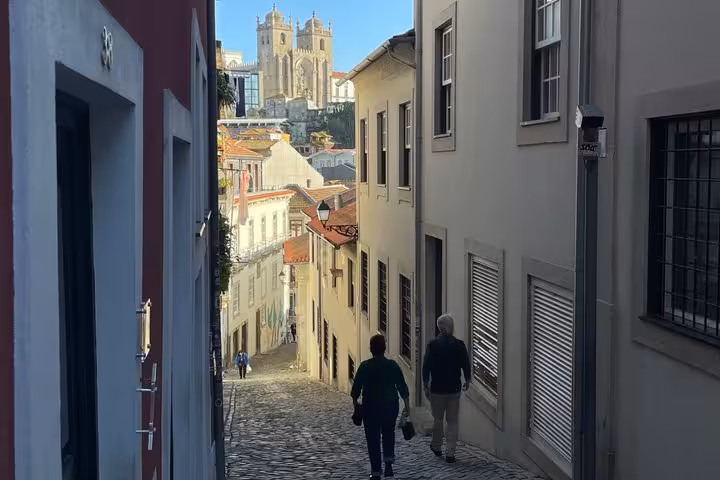 Tourists walking cobblestone alley in Porto old town with cathedral view on private history tour
