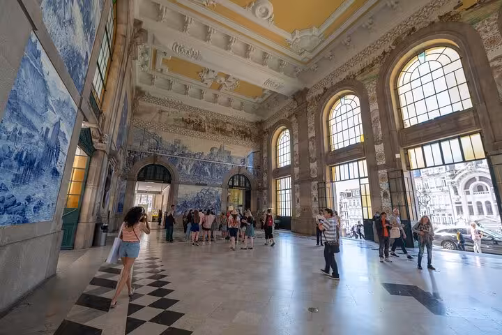 Tourists exploring the ornate azulejo tile hall of São Bento train station in Porto Old Town