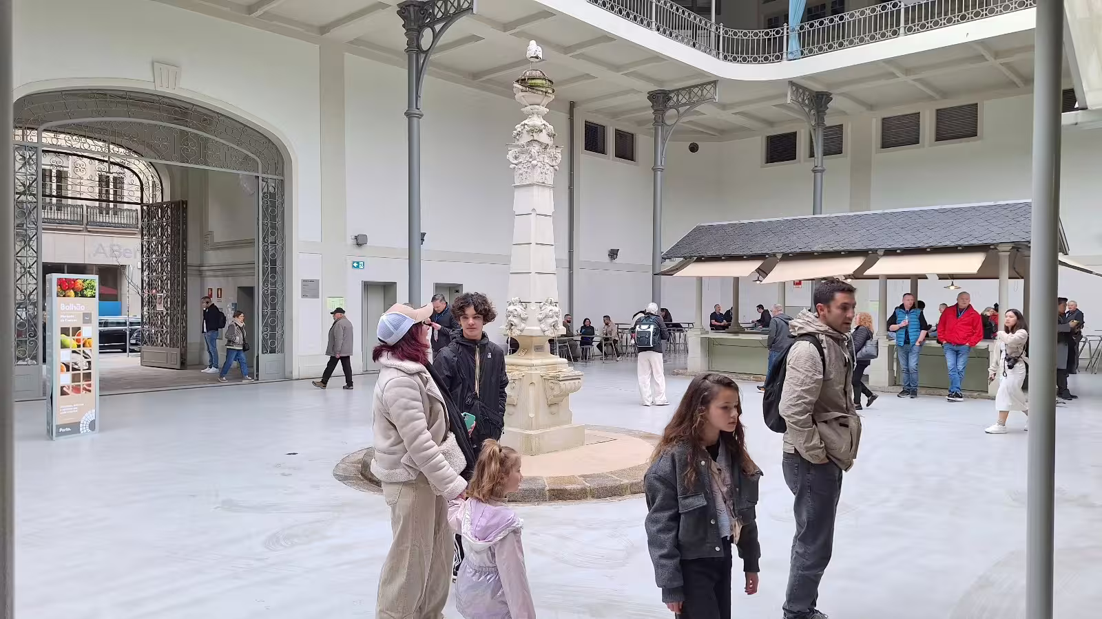 Visitors explore a historic indoor market in Porto on a private afternoon tour, showcasing local culture and architecture.