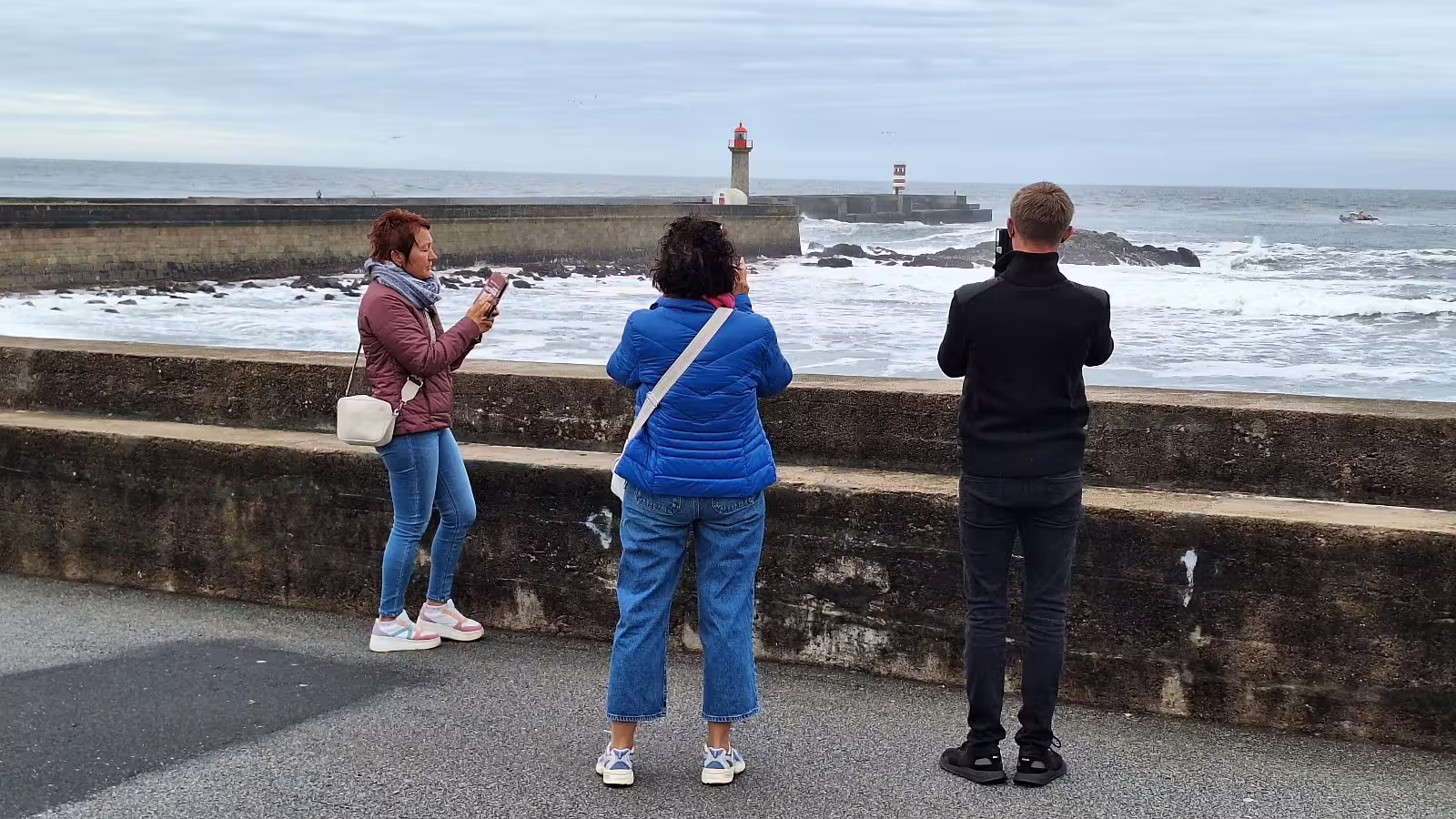 Tourists capture scenic views of Porto's iconic lighthouse and ocean waves during a private morning tour in Portugal.