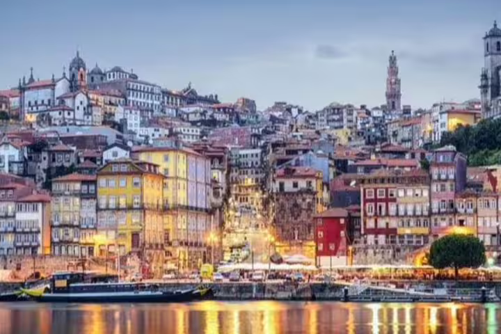 Porto's historic Ribeira District at dusk with colorful buildings reflecting in the Douro River, ideal for private tours in Portugal.