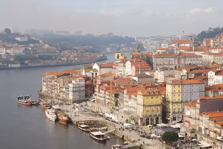 Aerial view of Porto's picturesque Ribeira District along the Douro River, with colorful buildings and boats docked nearby.