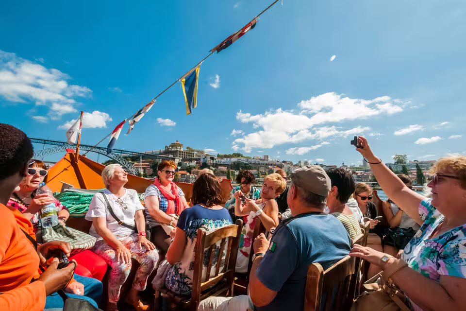 Tourists enjoying a sunny river cruise in Porto, capturing scenic views of the city's skyline and vibrant atmosphere.