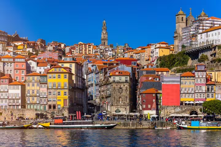 Colorful historic buildings along the Douro River waterfront in Porto, Portugal with Clerigos Tower in background