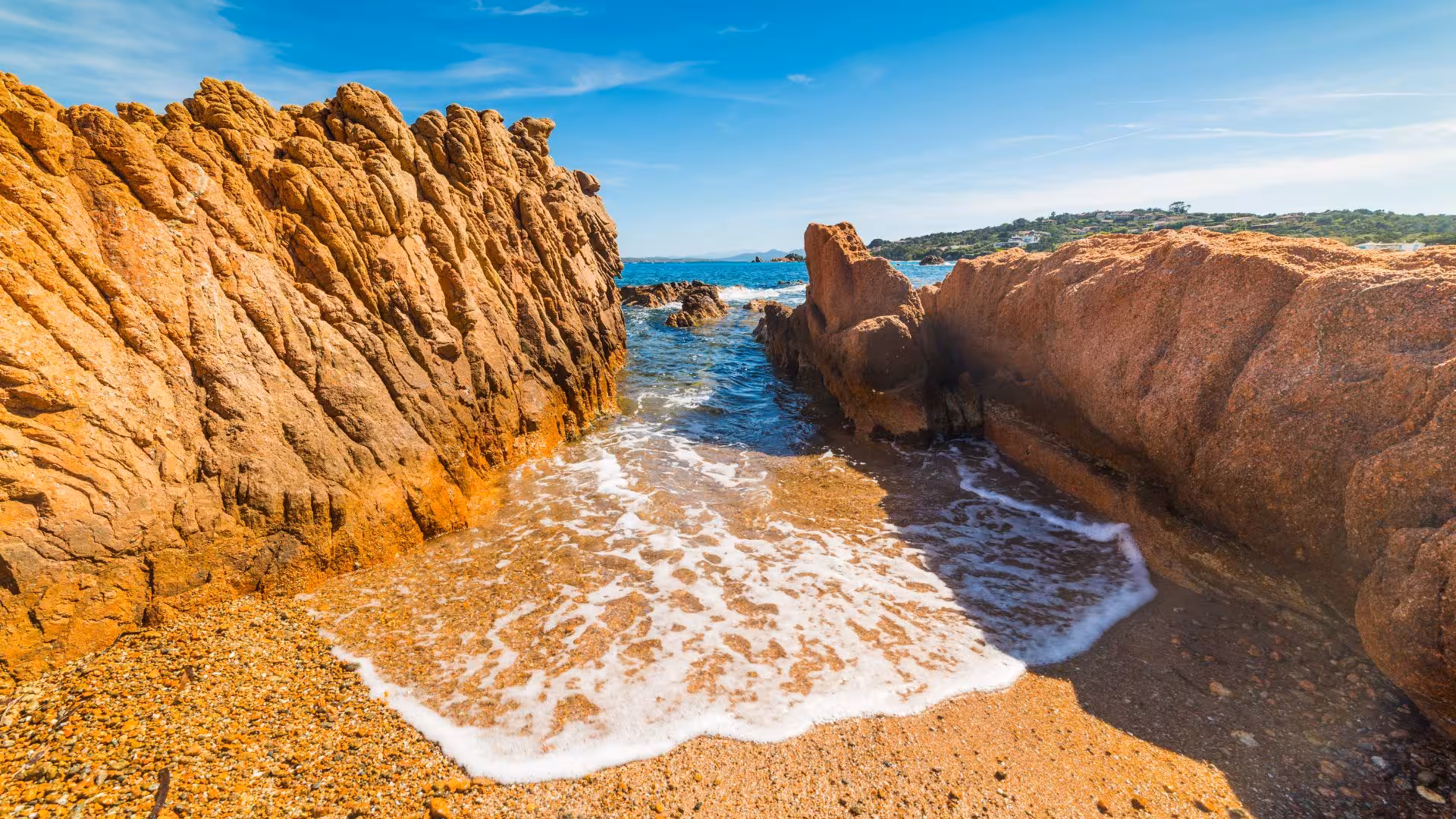 Golden rocky shoreline with clear blue water near Porto Rotondo, ideal for a scenic La Maddalena dinghy tour.
