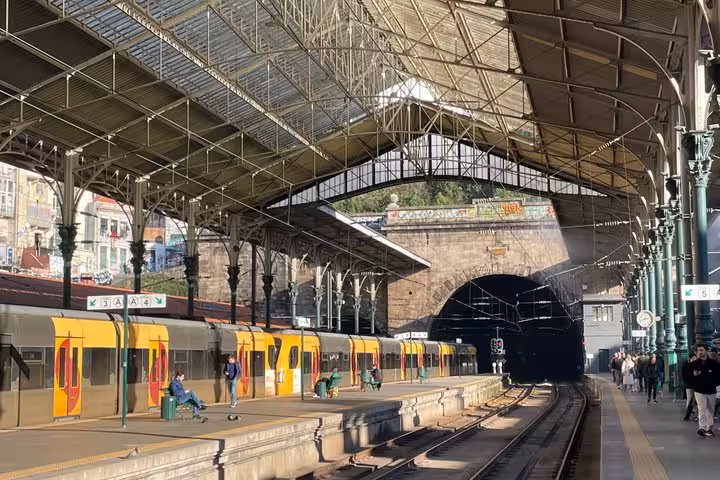 Historic Porto São Bento train station platform with yellow metro trains and iron roof on a walking tour