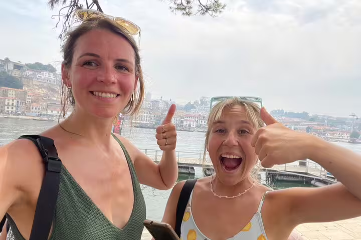 Two travelers giving thumbs up by the Douro River on a Porto scavenger hunt and sights self-guided tour