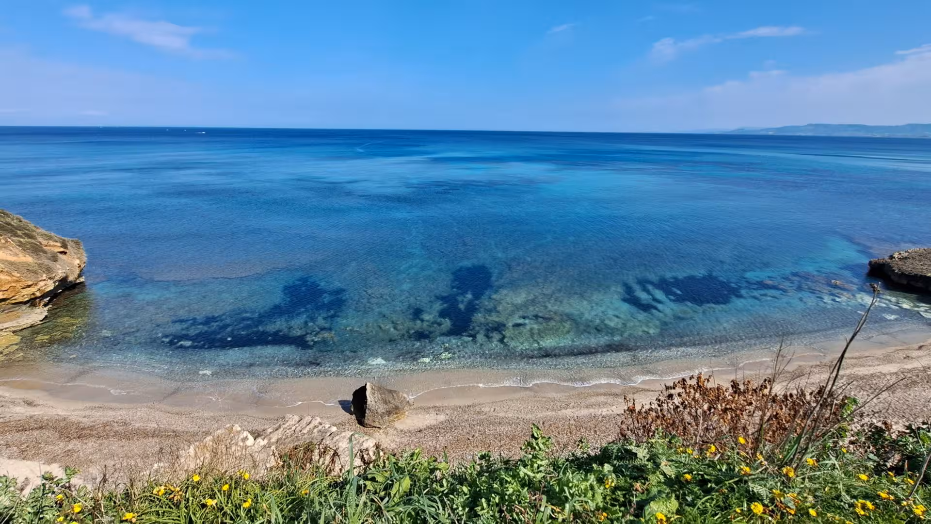 Tranquil beach in Porto Torres with turquoise waters and scenic views, perfect for diving baptism tours.