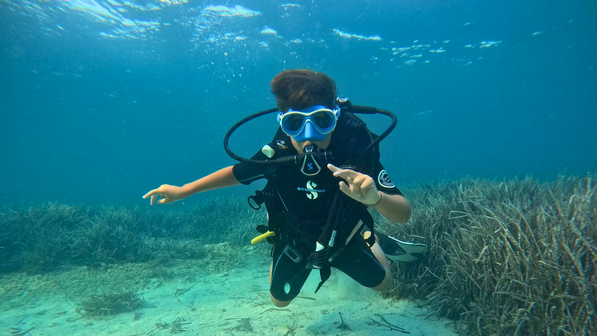 Young diver gliding over seagrass in Porto Torres, perfect for beginners experiencing their first diving baptism.