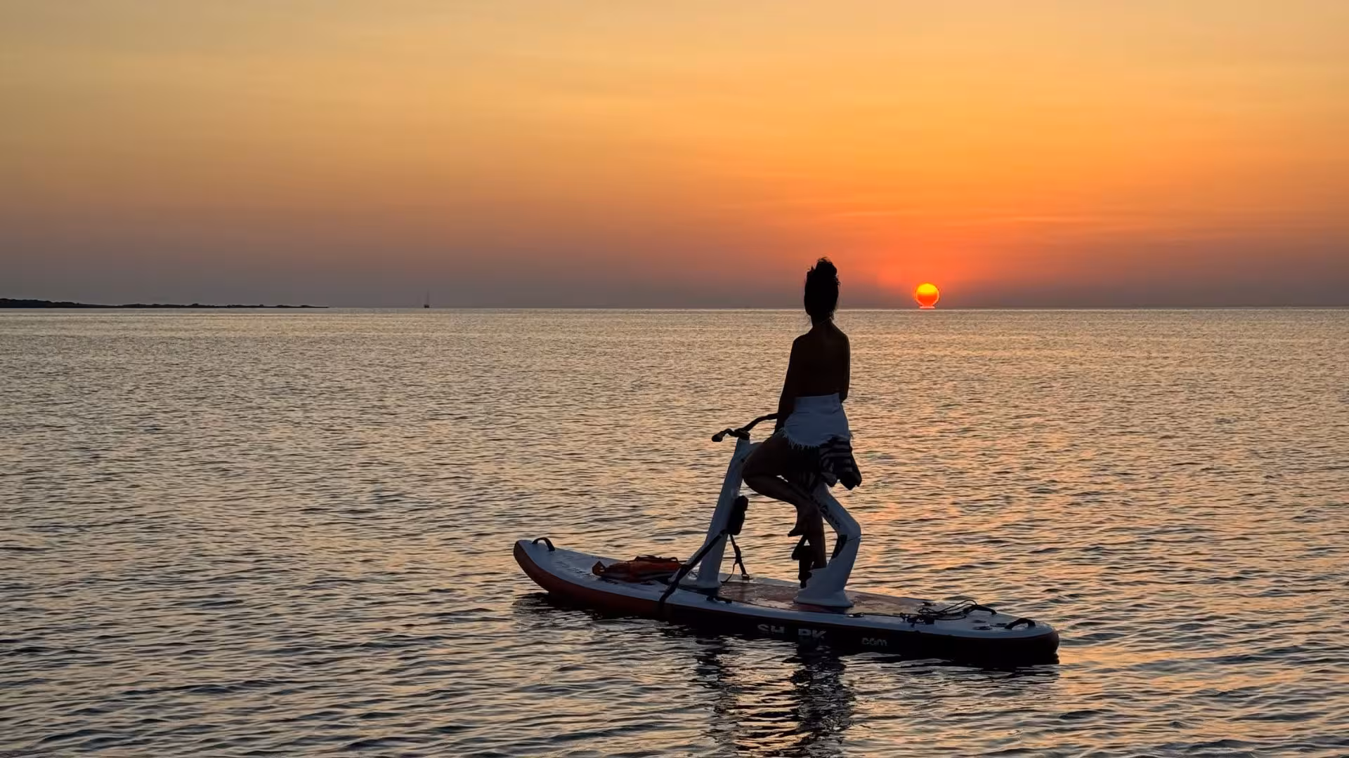 Water bike rider witnessing a breathtaking sunset over Porto Torres' calm waters.