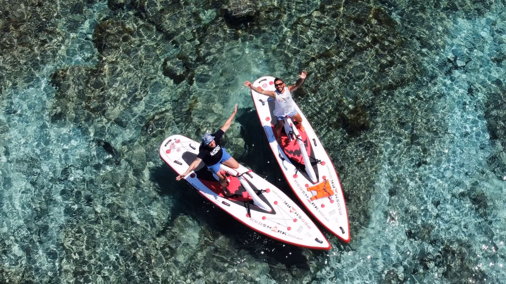 Close-up aerial shot of two people riding water bikes on the shimmering waters of Porto Torres, showcasing an exciting adventure.
