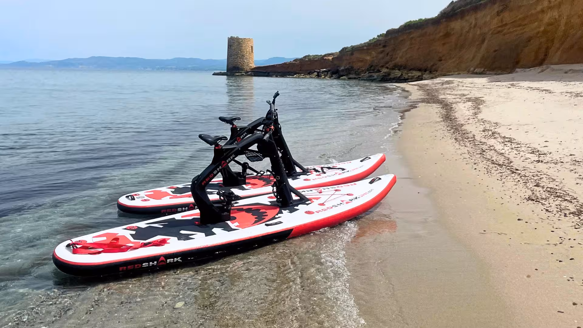 Water bikes on sandy Porto Torres beach with historic tower in the background, ideal for coastal tours.