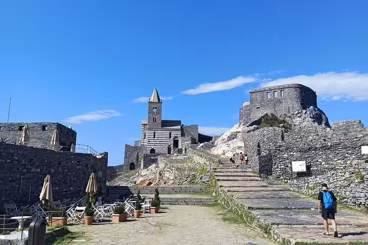 Visitor walking up to the historic Church of St Peter and stone fortifications in scenic Porto Venere on a private tour