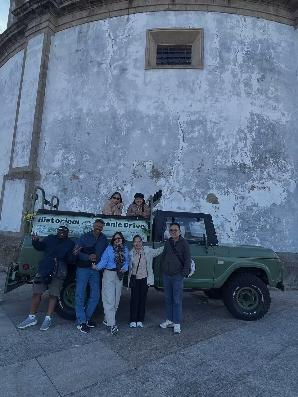 Guests pose by a vintage 4x4 on a Porto historical sites tour, scenic drive with Douro River views
